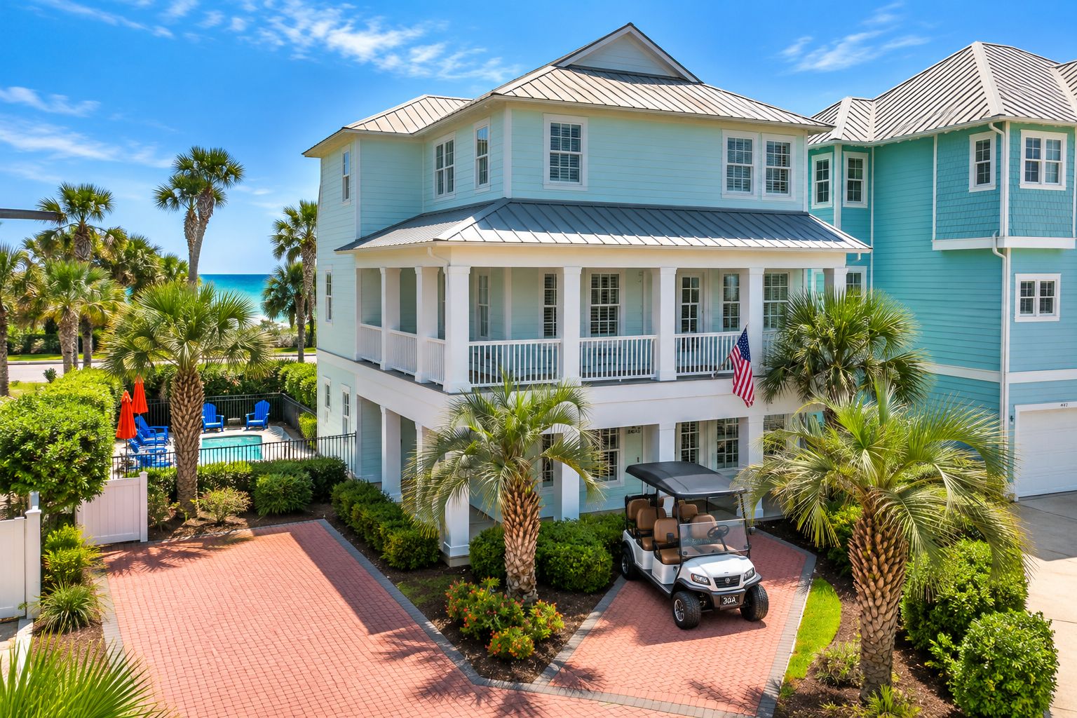 A two-story building with a pool, palm trees, and a golf cart.