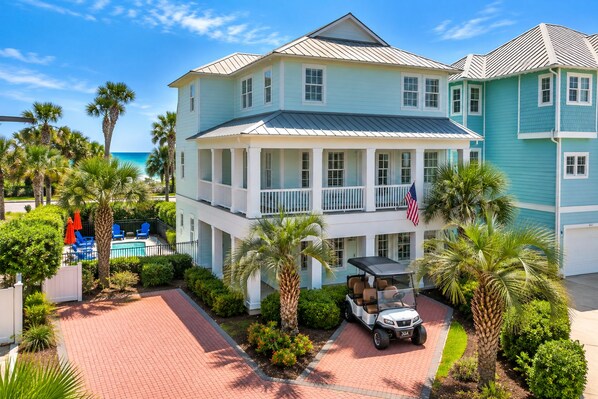 A two-story building with a pool, palm trees, and a golf cart. - Steps2 Beach/Gulf Views/Heated Pool&Spa/Golf Cart (Destin)