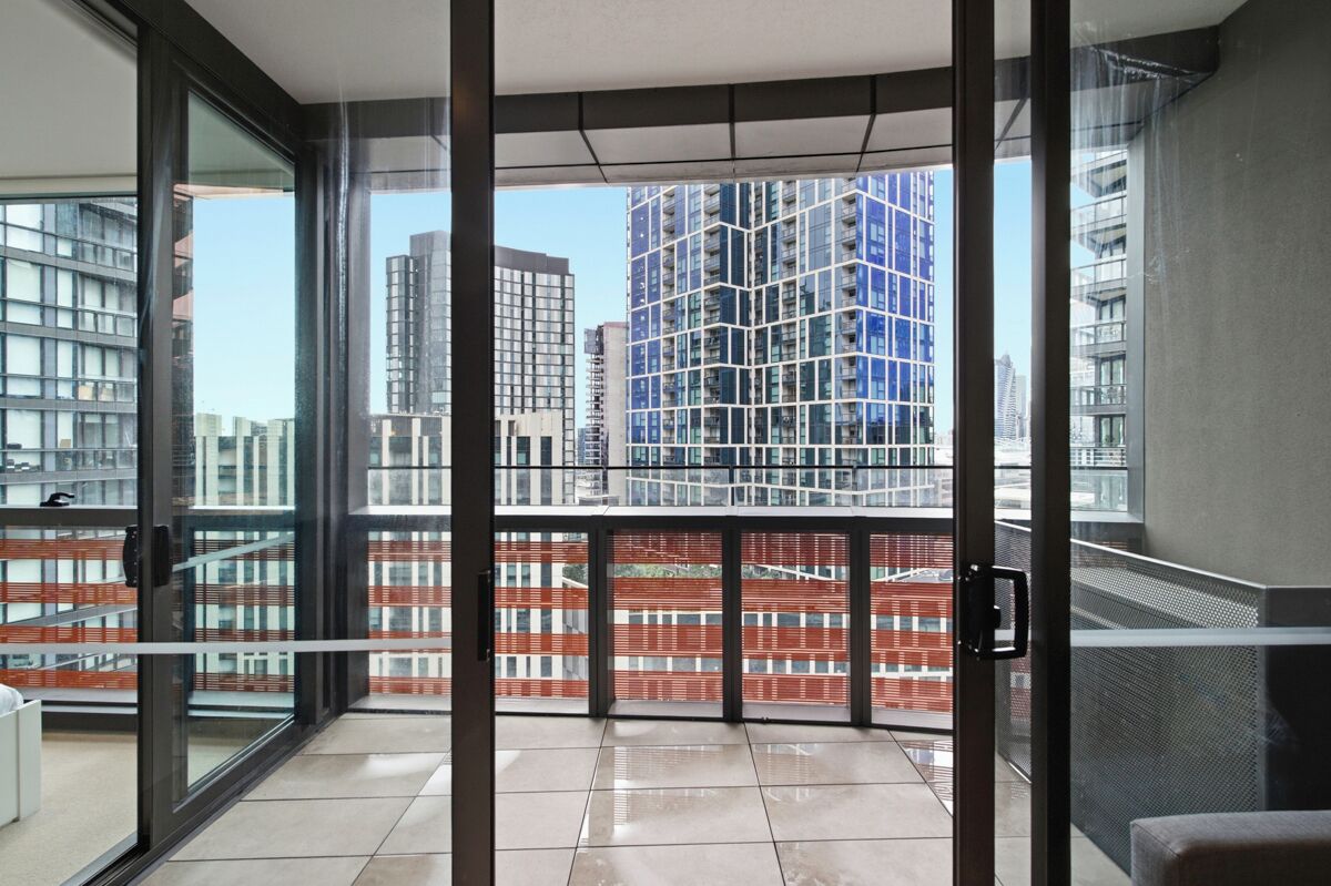 Un appartement moderne doté d’un balcon, de grandes fenêtres et offrant une vue sur les immeubles de grande hauteur.