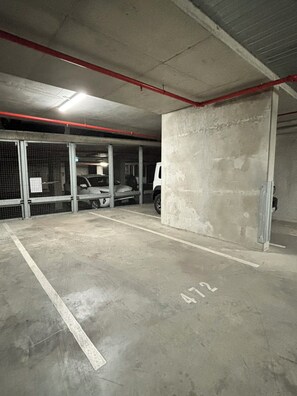A parking garage with concrete floors, marked parking spaces, and metal security fencing. - Melbourne Executive Suites | Collins Street | Docklands | Free Parking Onsite (Docklands)