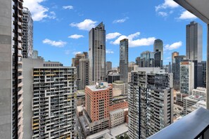 A high-rise urban skyline with multiple buildings, including a prominent red-brick structure and several modern glass skyscrapers. - High-Rise 1-Bed Apartment Near Southern Cross (Melbourne)