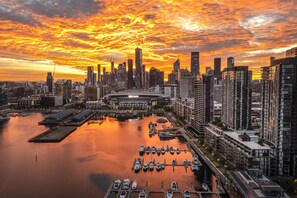 A city skyline at sunset with a marina and a stadium. - High-Rise 1-Bed Apartment Near Southern Cross (Melbourne)