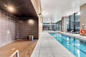 Ein moderner, überdachter Schwimmbereich mit klarem Wasser und gefliesten Wänden.