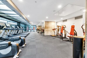 A gym with treadmills, elliptical machines, and weightlifting equipment. - High-Rise 1-Bed Apartment Near Southern Cross (Melbourne)