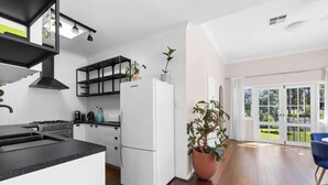 Eine moderne Küche mit weißen Schränken, einer schwarzen Arbeitsplatte und einem großen Fenster.