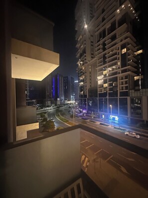 A nighttime view of a modern urban area with high-rise buildings, a curved road, and illuminated signage. - Villa (Dubai)