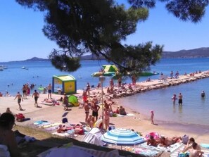 Ein Strand mit Menschen, die sich sonnen, schwimmen und am Ufer entlanggehen.