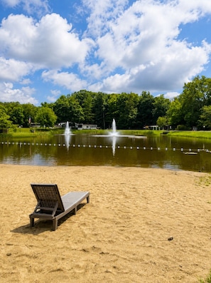 Une plage de sable avec un fauteuil de plage et un étang doté de fontaines.