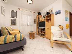 A living room with a sofa, a chair, a TV stand, and a cabinet. - Apartment Lu by Interhome (Krk/Milohnići)