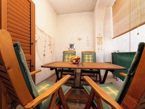A small dining area with a wooden table and four green upholstered chairs. - Apartment Lu by Interhome (Krk/Milohnići)