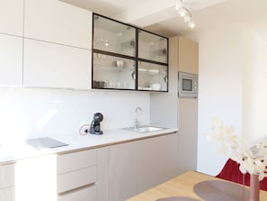 A modern kitchen with a built-in microwave, a coffee machine, and a glass-fronted cabinet. - Apartment Basilea - 03 by Interhome (Krk/Milohnići)