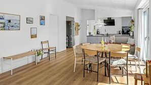 Eine moderne Küche mit Einbauofen und Mikrowelle, ein Essbereich mit Holztisch und Stühlen sowie eine Bank an der Wand.