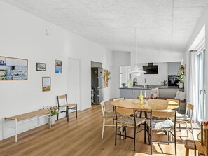 Eine moderne Küche mit Einbauofen und Mikrowelle, ein Essbereich mit Holztisch und Stühlen sowie eine Bank an der Wand.