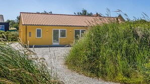 Ein gelbes Gebäude mit einem Ziegeldach und einer Schotterauffahrt, die zu einer Glastür führt.