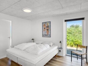A bedroom with a bed, a nightstand, a chair, a poster, and a view of greenery through a door. - "Lars" - 350m from the sea by Interhome (Løkken)