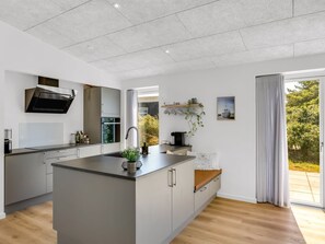A modern kitchen with a central island, built-in appliances, and a large window. - "Lars" - 350m from the sea by Interhome (Løkken)