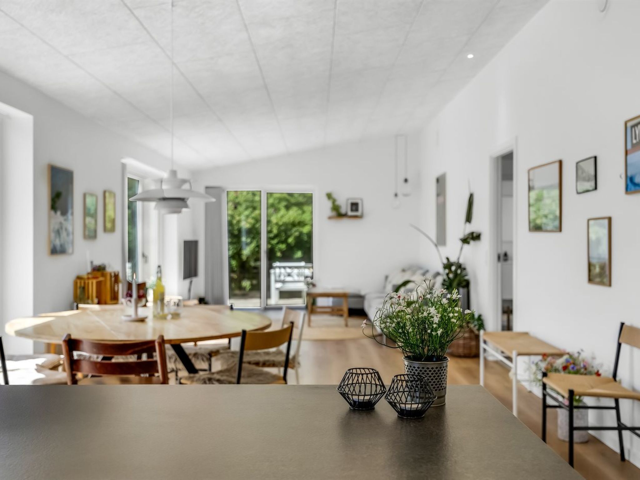 Un comedor amplio con una mesa redonda, sillas y un jarrón con flores.