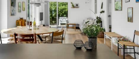 A spacious dining area with a round table, chairs, and a vase with flowers.