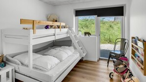 Ein Schlafraum mit Etagenbett, Fenster und einem Stoffbären.