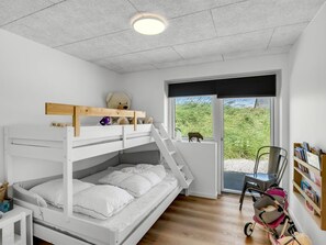 Ein Schlafraum mit Etagenbett, Fenster und einem Stoffbären.