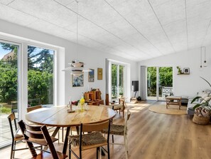 A spacious dining area with a round table and chairs, large windows, and a view of greenery outside. - "Lars" - 350m from the sea by Interhome (Løkken)