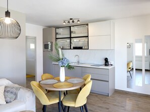 Eine moderne Küche mit Kochinsel, einem Essbereich mit gelben Stühlen und einem weißen Sofa.