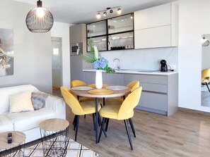 Eine moderne Küche mit Essbereich, einem weißen Sofa und einer Kaffeemaschine.