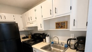 A compact kitchen with white cabinets, a black refrigerator, a stove, a sink, and a coffee maker. - Modern 1BR King Bed Near Downtown Birmingham & UAB (Birmingham)