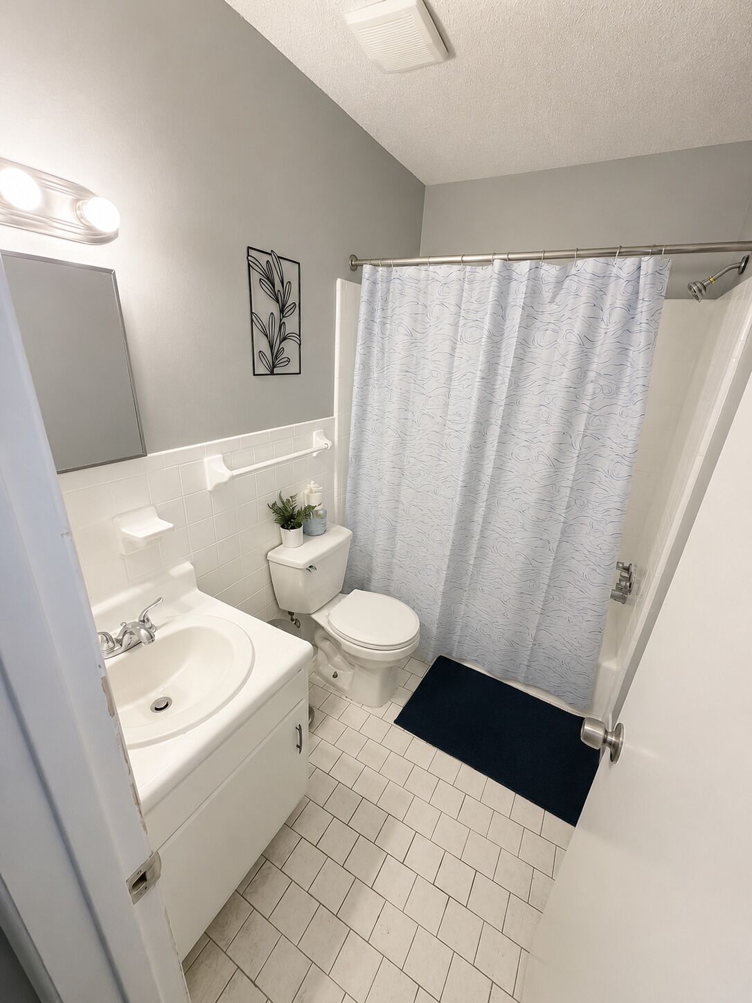 A bathroom with a toilet, sink, and shower curtain.