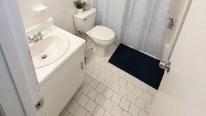A bathroom with a toilet, sink, and shower curtain. - Modern 1BR King Bed Near Downtown Birmingham & UAB (Birmingham)