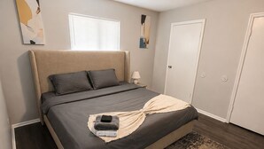 A bedroom with a bed, a bedside table, a lamp, a window, and a door. - Modern 1BR King Bed Near Downtown Birmingham & UAB (Birmingham)
