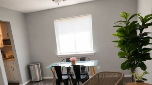 A modern living room with a dining area, a large window, and a potted plant. - Modern 1BR King Bed Near Downtown Birmingham & UAB (Birmingham)
