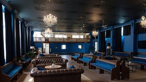 A spacious lounge with leather sofas, wooden benches, and a high ceiling with chandeliers. - Temple Backpackers (Cairns)