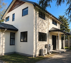 Ein zweistöckiges Haus mit einer überdachten Veranda, einer Garage und einem Rasen.
