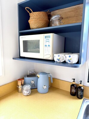 Eine Küche mit Mikrowelle, Toaster, Wasserkocher und verschiedenen Behältern.