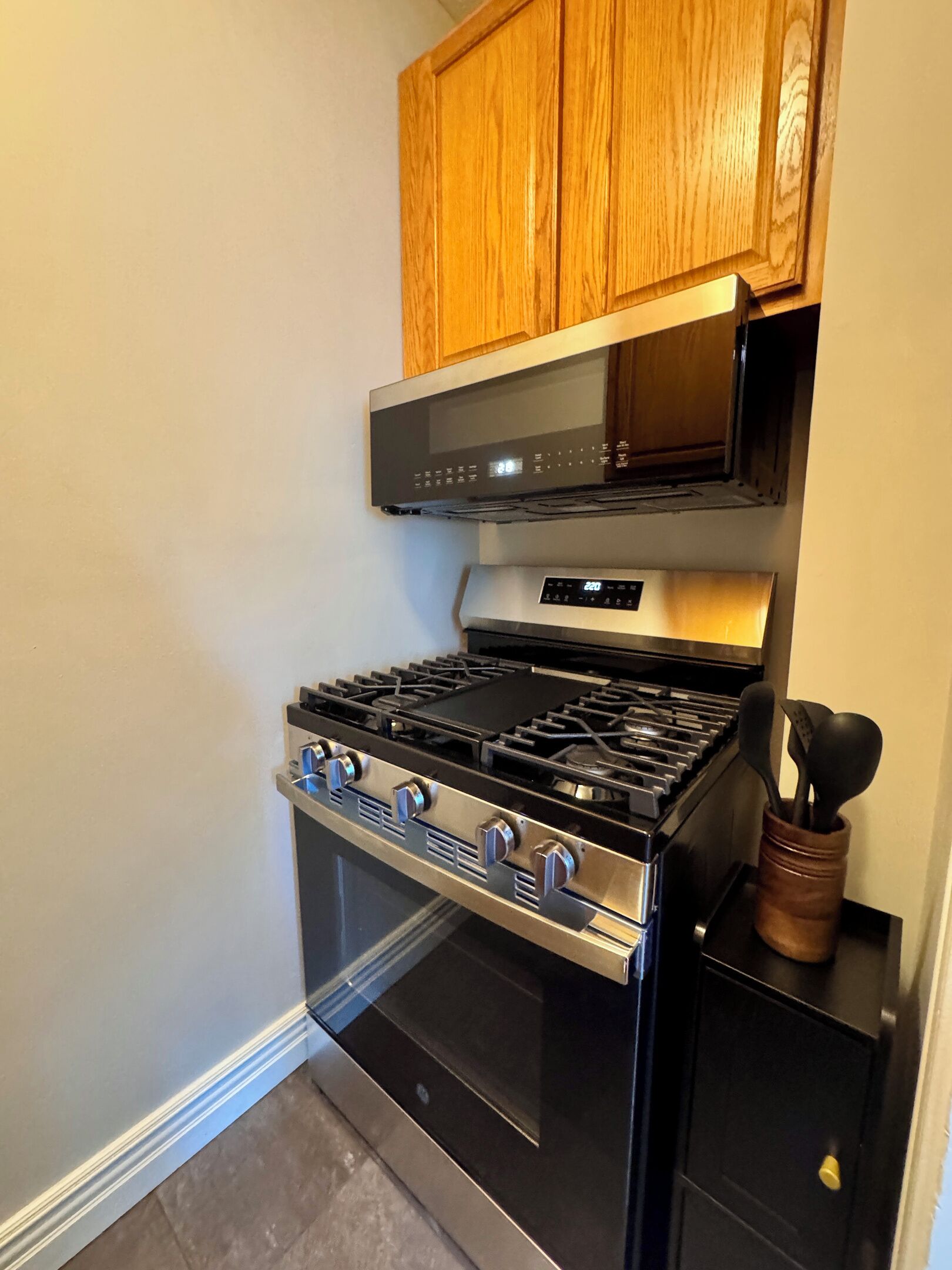 A kitchen with a black stove, wooden cabinets, and a stainless steel range hood.