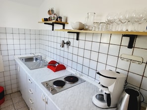 A compact kitchen with a sink, two burners, a coffee maker, and a red utensil holder. - Apartment Italo - 2 by Interhome (Krk/Njivice)
