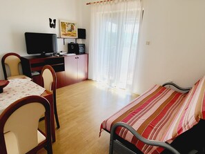 Ein Schlafzimmer mit einem Bett, einem Schreibtisch mit Computer, einem Stuhl und einem fenster mit Vorhängen.