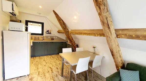 A kitchen with a white refrigerator, a wooden beam ceiling, and a dining table with chairs.