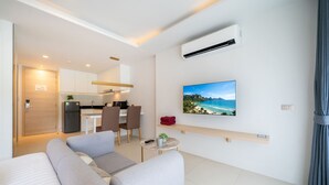 A modern living room with a sofa, a small table, and a TV mounted on the wall. - Modern Studio Rooftop Pools UTKR 205 (Tambon Karon)