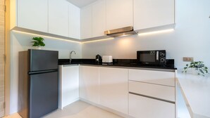 A modern kitchen with white cabinets, a black refrigerator, a microwave, and a coffee maker. - Modern Studio Rooftop Pools UTKR 205 (Tambon Karon)