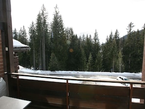 A view from a balcony with a wooden railing, overlooking a snowy landscape with dense evergreen trees and a road. - I dr Rehwiesa A32 Appartement/Fewo, Bad, WC, 2-Bettwohnung 2-Bettwohnung by Interhome (Arosa)