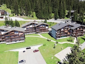 Um hotel moderno de vários andares com um pátio central, rodeado por uma floresta densa.