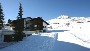 Ein mehrstöckiges Gebäude mit einer Skipiste im Hintergrund.