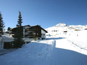 Ein mehrstöckiges Gebäude mit einer Skipiste im Hintergrund.