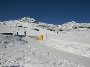 Ein verschneiter Berghang mit Skifahrern und einer gelben Absperrung.
