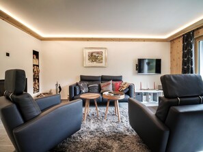 A modern living room with a sofa, two armchairs, a coffee table, and a flat-screen TV mounted on the wall. - Chalet Steinbock by Arosa Holiday Appartement/Fewo, Bad, WC, 3 Schlafräume by Interhome (Arosa)
