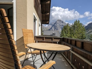 A wooden deck with a round table and chairs, overlooking a mountainous landscape. - Chalet Steinbock by Arosa Holiday Appartement/Fewo, Bad, WC, 3 Schlafräume by Interhome (Arosa)