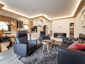 A modern living room with a fireplace, seating area, and a kitchen visible through an archway. - Chalet Steinbock by Arosa Holiday Appartement/Fewo, Bad, WC, 3 Schlafräume by Interhome (Arosa)