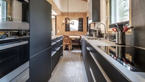 A modern kitchen with a wooden ceiling, a dining area, and a view of the outdoors. - Chalet Steinbock by Arosa Holiday Appartement/Fewo, Bad, WC, 3 Schlafräume by Interhome (Arosa)